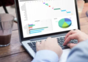 pessoa mexendo no computador analisando gráficos para ilustrar a coleta de dados do varejo
