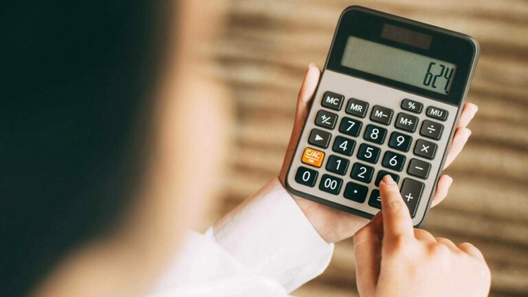 Pessoa fazendo uma conta na calculadora para ilustrar o cálculo do cpv custo do produto vendido