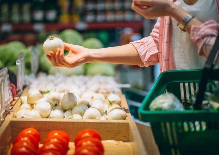 Pessoa escolhendo alho no mercado para ilustrar o ato de escolher produtos