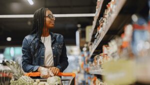 Mulher no mercado olhando as prateleiras para ilustrar o monitoramento de concorrência