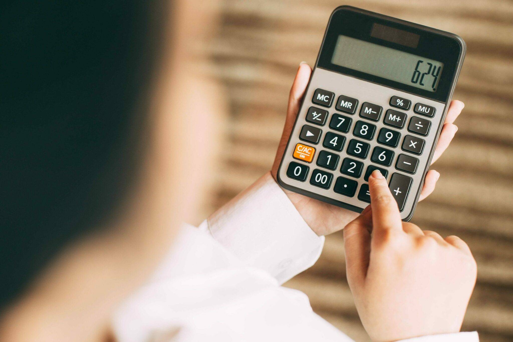 Pessoa fazendo uma conta na calculadora para ilustrar o cálculo do cpv custo do produto vendido