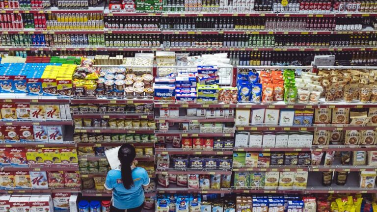 várias gôndolas de um supermercado com um pesquisador de preços
