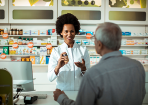 Farmacêutica atendendo um cliente idoso na farmácia, para ilustrar o uso do PBM nas farmácias